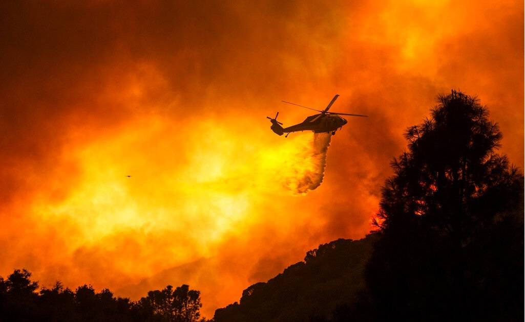 A helicopter drops water to the Lake Fire near Lake Hughes in the Angeles National Forest on Wednesday, Aug. 12, 2020, north of Los Angeles , Calif. (AP Photo/Ringo H.W. Chiu)