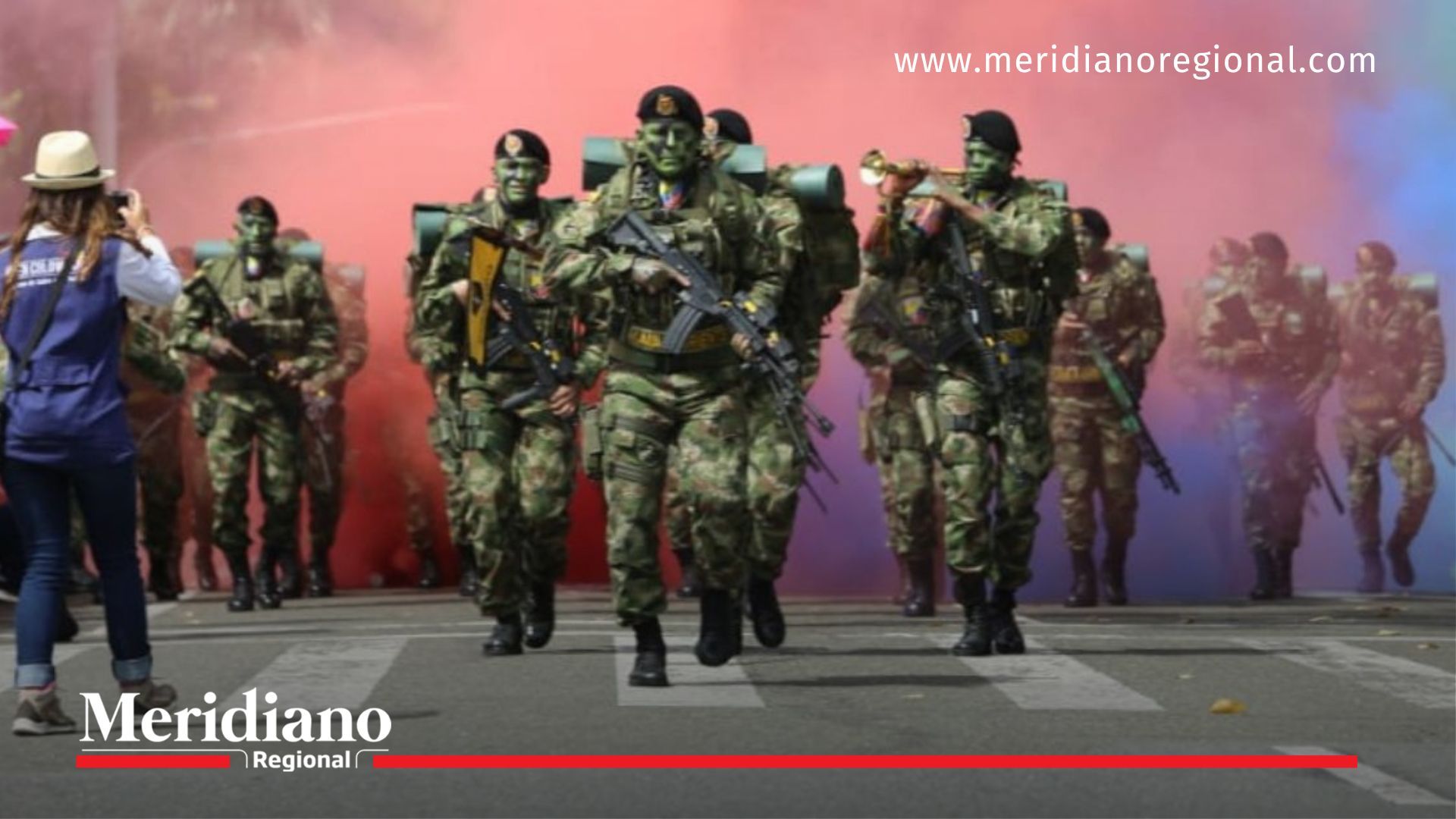 Soldados del Ejército Nacional desfilan con humo tricolor durante acto del Día de la Independencia en Colombia.