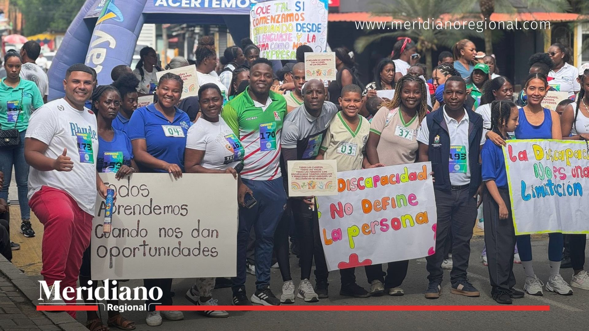 Grupo de participantes en la Maratón de los Sueños en Puerto Tejada sosteniendo carteles con mensajes de inclusión, igualdad y esperanza.