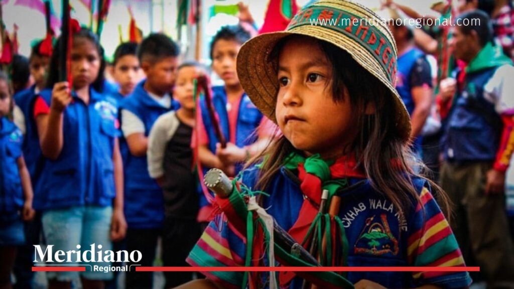 Niña Nasa con vestimenta tradicional y bastón de mando participa en un evento de su cabildo indígena en el Cauca, símbolo de resistencia y unidad.