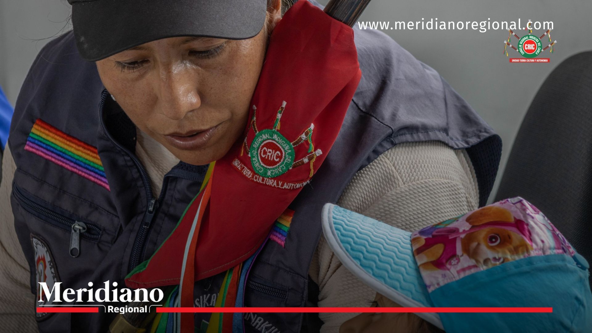 Mujer del CRIC Cauca con bastón de mando y niña durante actividad comunitaria