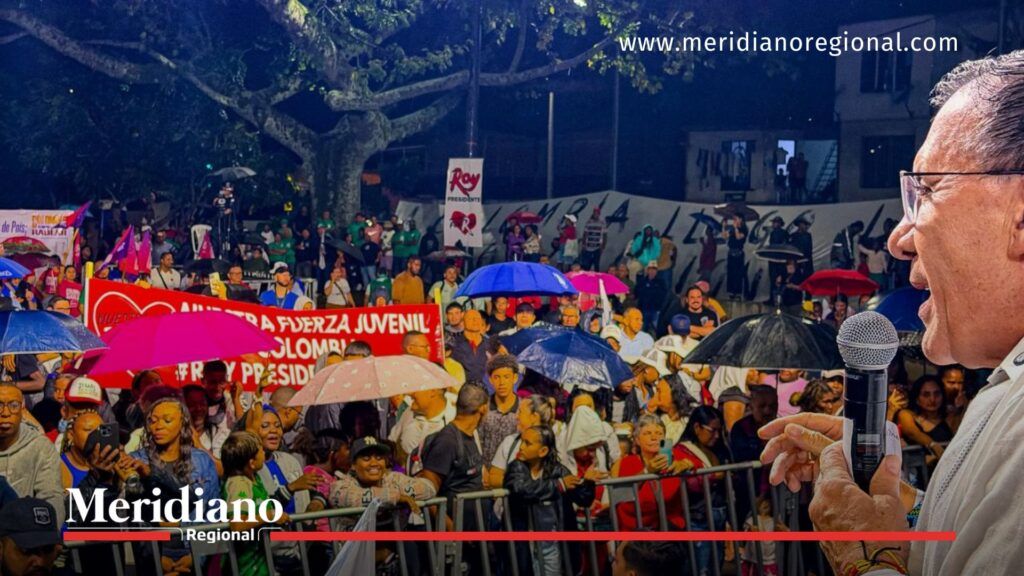 Roy Barreras presenta en Cali su estrategia Seguridad Total ante una multitud con paraguas durante un acto público en el Bulevar de Oriente.