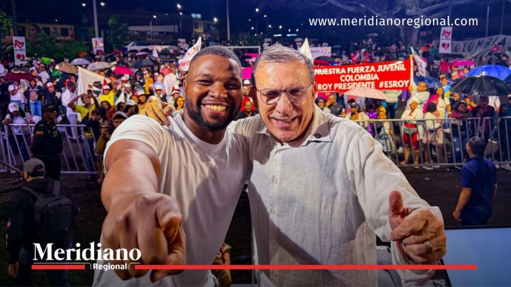 Roy Barreras se toma una foto con un asistente durante el lanzamiento de Seguridad Total en Cali, con una multitud al fondo.