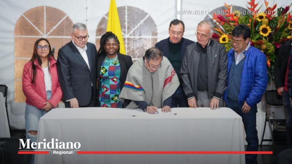 Gustavo Petro firma un documento oficial junto a su gabinete en un evento público, en contexto del debate nacional sobre los gestores de paz.