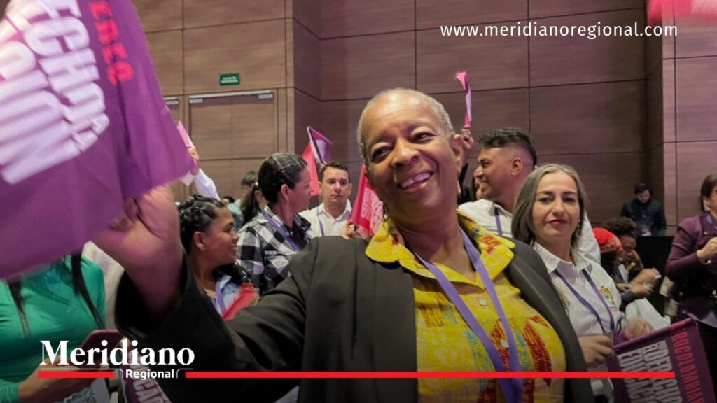 Sor Inés Larrahondo Carabalí en el Foro Educativo Nacional 2025 - Meridiano Regional Sor Inés Larrahondo Carabalí sonríe y sostiene una bandera durante el Foro Educativo Nacional 2025, rodeada de asistentes en el auditorio.