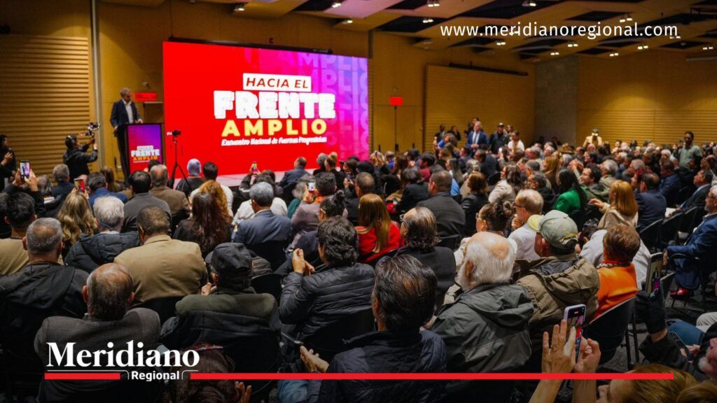 Público asistente a un evento del Frente Amplio observando la tarima durante los preparativos para la consulta interpartidista.
