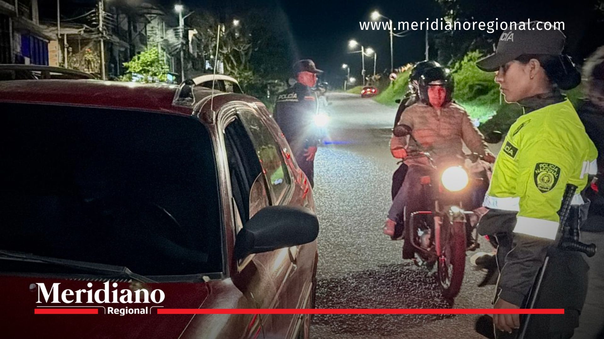 Una uniformada de la Policía Nacional solicita documentos a un conductor durante un control vehicular nocturno en Popayán.