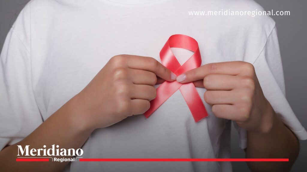 Día Mundial contra el Cáncer: mujer sostiene lazo rosado en el pecho como símbolo de prevención del cáncer de mama