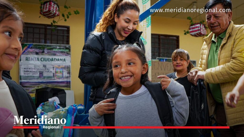 Niña del Cauca recibe mochila escolar durante jornada del programa Cafeciendo Sueños acompañada por la gestora social.