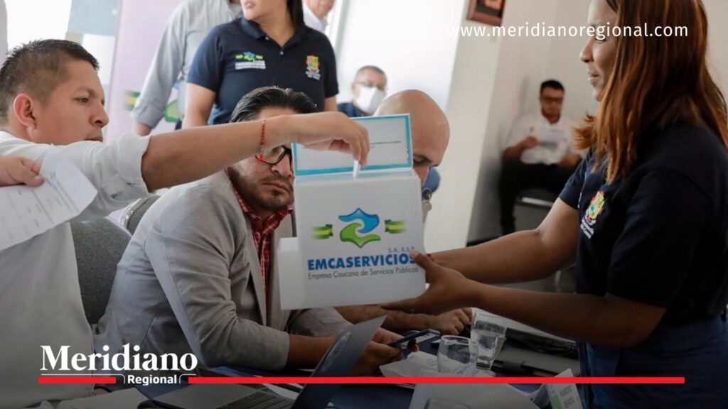 Votación en asamblea de Emcaservicios en el Cauca - Meridiano Regional Asistente deposita voto en urna de Emcaservicios durante asamblea con participación de autoridades y representantes municipales.