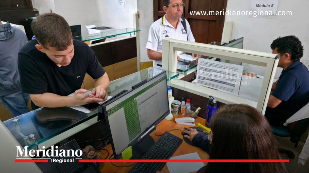Ciudadano realiza pago en ventanilla de atención mientras funcionario registra la información en un computador en oficina administrativa del Cauca