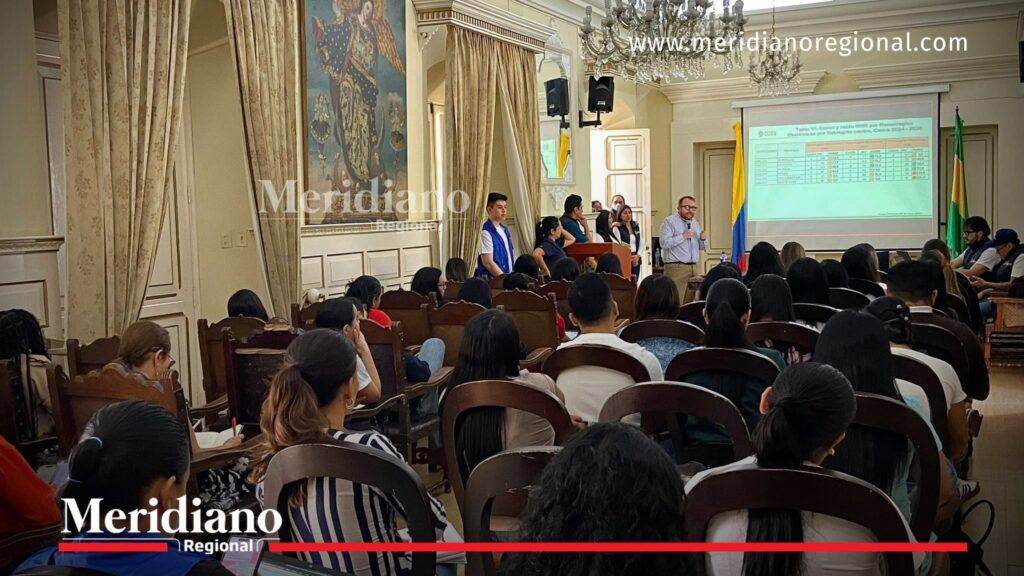 Asistentes en salón institucional durante Mesa PARE en Cauca, escuchando presentación sobre indicadores de salud materna con proyección en pantalla.