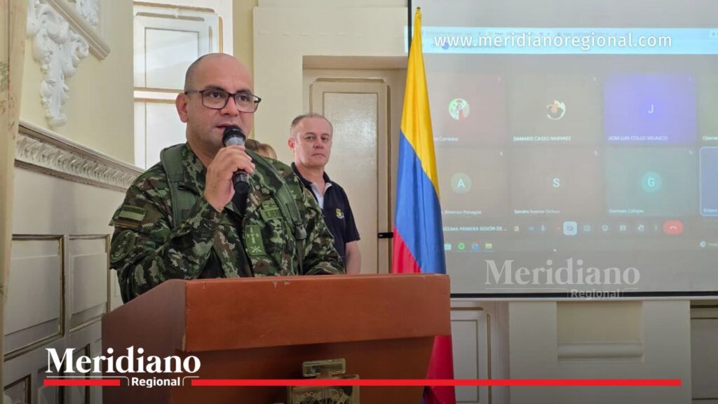 Oficial de la Fuerza Pública interviene en reunión de coordinación electoral en el Cauca con bandera de Colombia y participantes conectados por videoconferencia.