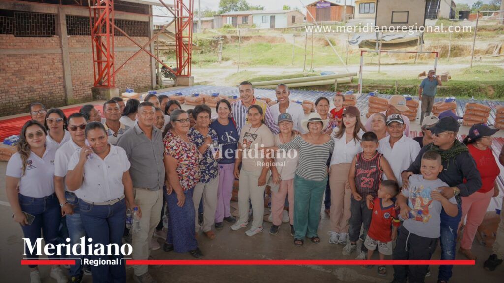 Gobernador Jorge Octavio Guzmán junto a familias beneficiarias de El Carmelo, en Cajibío, durante la entrega de ayudas integrales para la reconstrucción de viviendas, con materiales de construcción dispuestos al fondo de la jornada organizada por la Gobernación del Cauca.