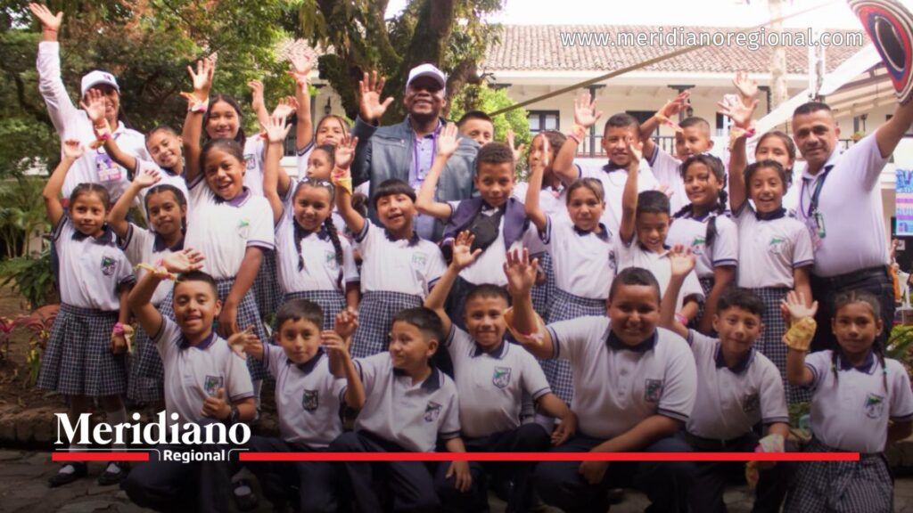 Grupo de niñas, niños y acompañantes posa con entusiasmo durante el encuentro Artes para la Paz realizado en Cauca, levantando las manos en un espacio de integración cultural.