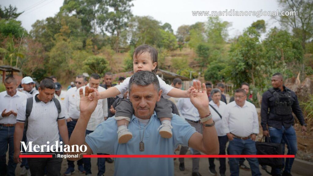 Habitante con un niño sobre sus hombros recorre la nueva placa huella en El Túnel, Cajibío, junto a la comunidad y representantes institucionales.