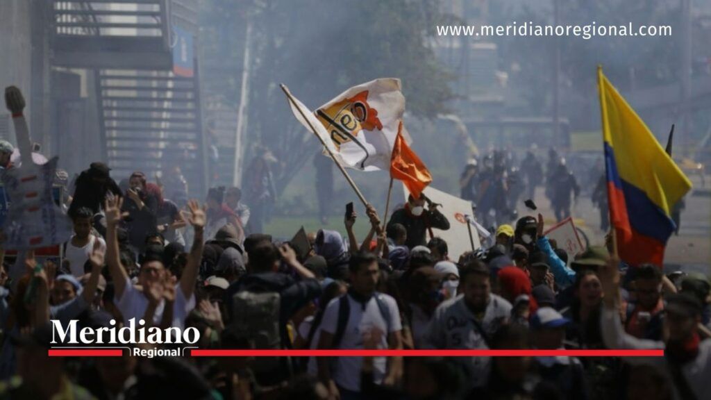 Manifestantes durante una protesta en Colombia con banderas nacionales.
