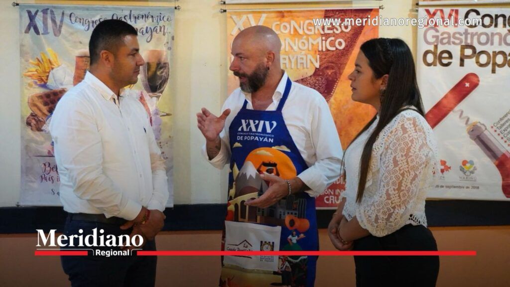 Participantes del Congreso Gastronómico de Popayán. - Meridiano Regional Tres personas conversan frente a carteles de anteriores ediciones del Congreso Gastronómico de Popayán.
