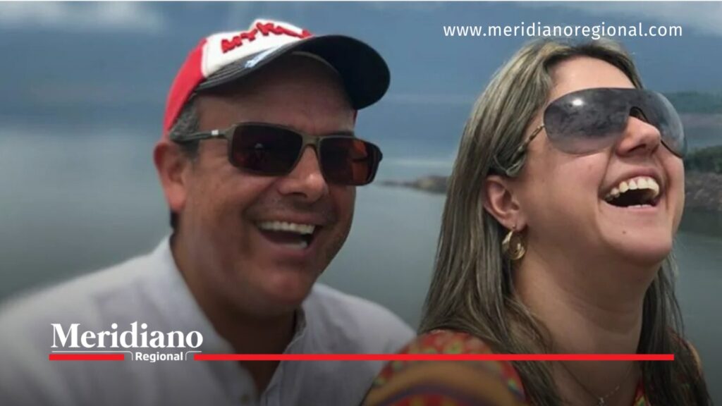 Ricardo Orrego y su esposa aparecen sonrientes, utilizando gafas de sol, durante un momento al aire libre con un paisaje acuático de fondo.