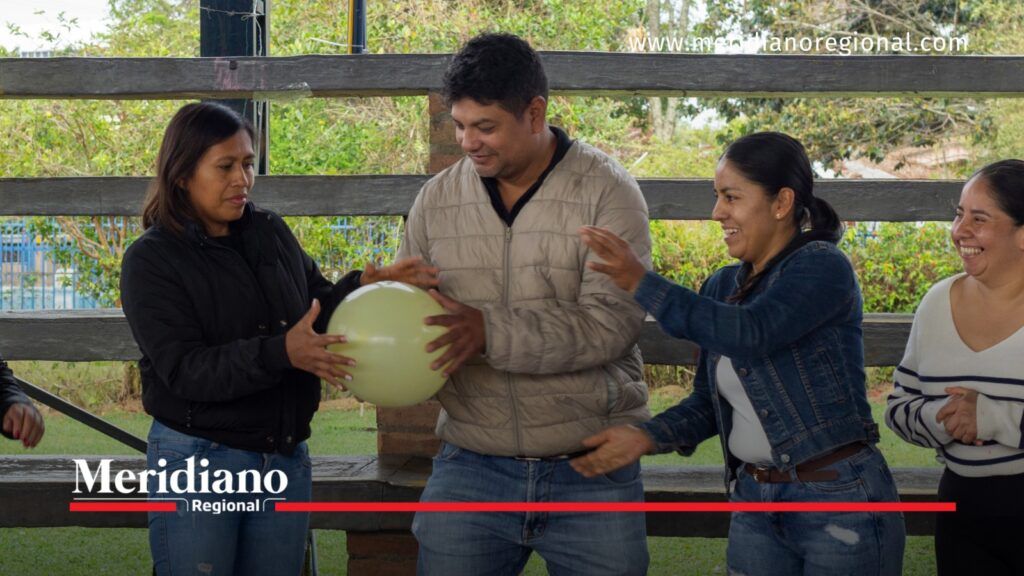 Tres adultos participan en una dinámica grupal con un globo verde mientras otra mujer observa durante una jornada en Salesianas.