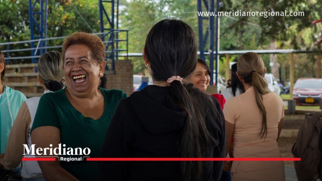 Mujer con blusa verde sonríe mientras comparte con otras participantes durante una actividad de integración familiar.
