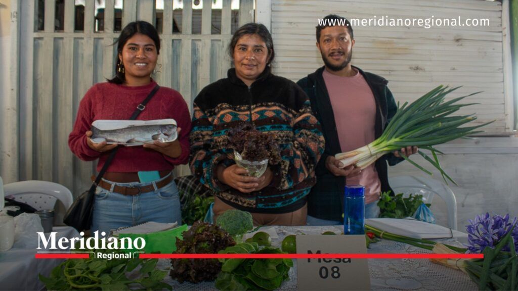 Tres participantes muestran pescado, lechugas y cebollas largas en un puesto de productos locales de la Plaza Las Palmas de Popayán.