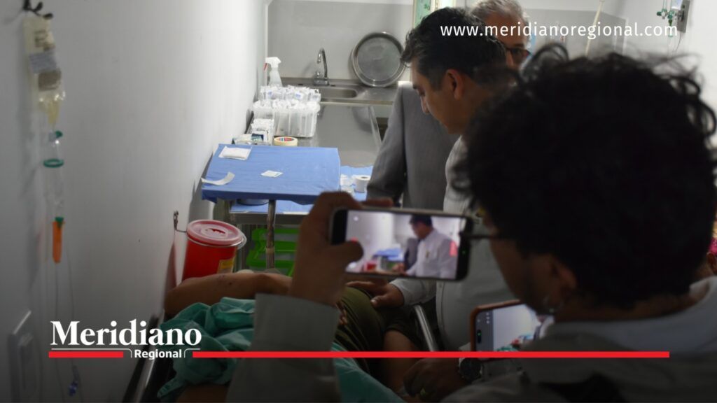 Personas acompañan a un paciente en una camilla hospitalaria mientras se registra la atención médica con teléfonos celulares.