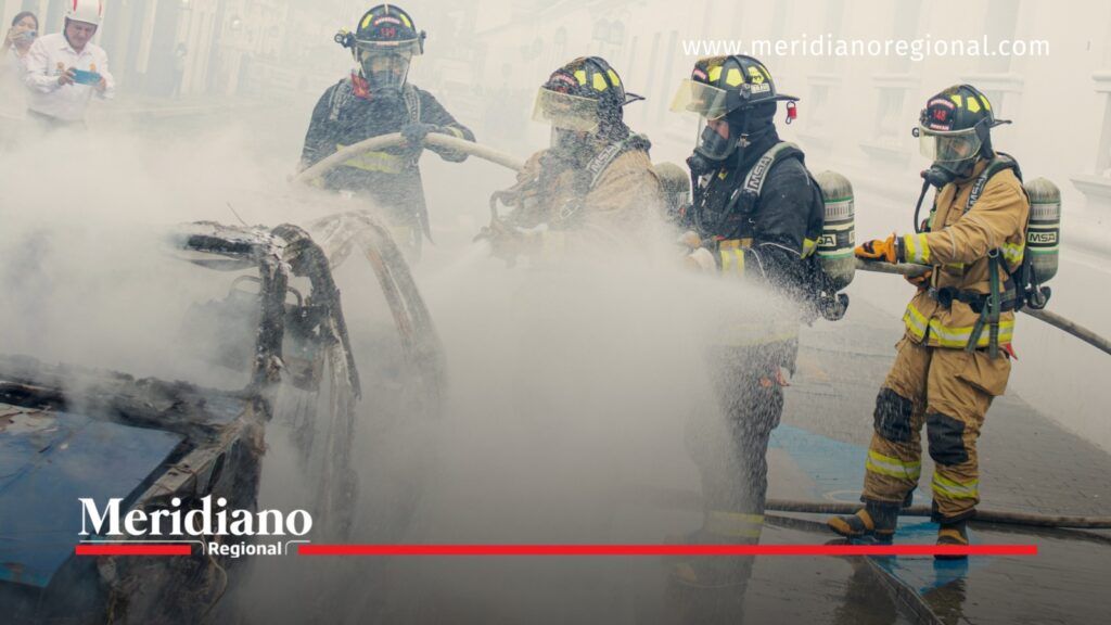 Bomberos con equipos de protección y mangueras realizan labores de extinción de un incendio en un vehículo en Popayán, Cauca.