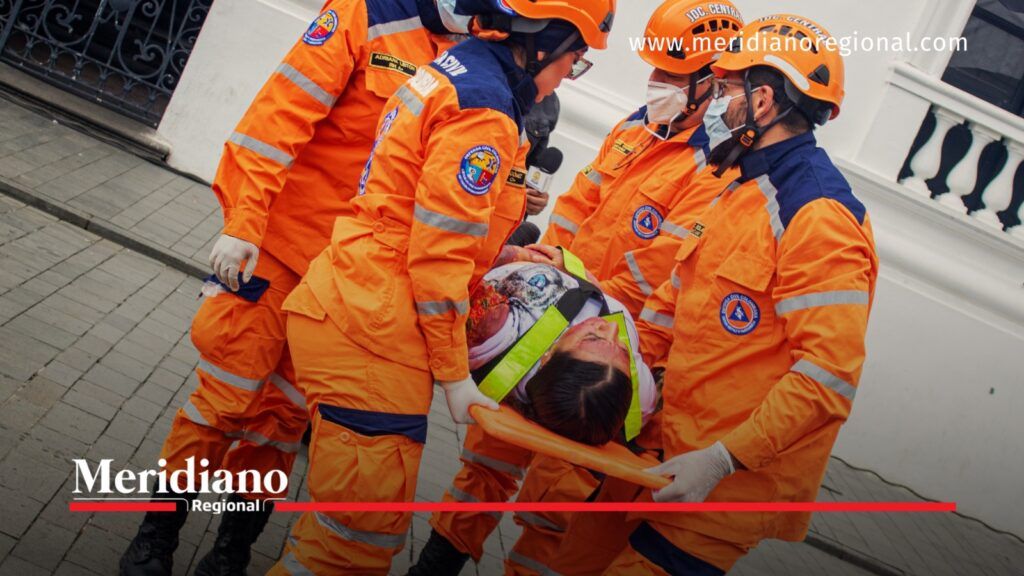 Cuatro socorristas de la Defensa Civil trasladan en camilla a una persona con heridas simuladas durante un ejercicio de emergencia en Popayán.