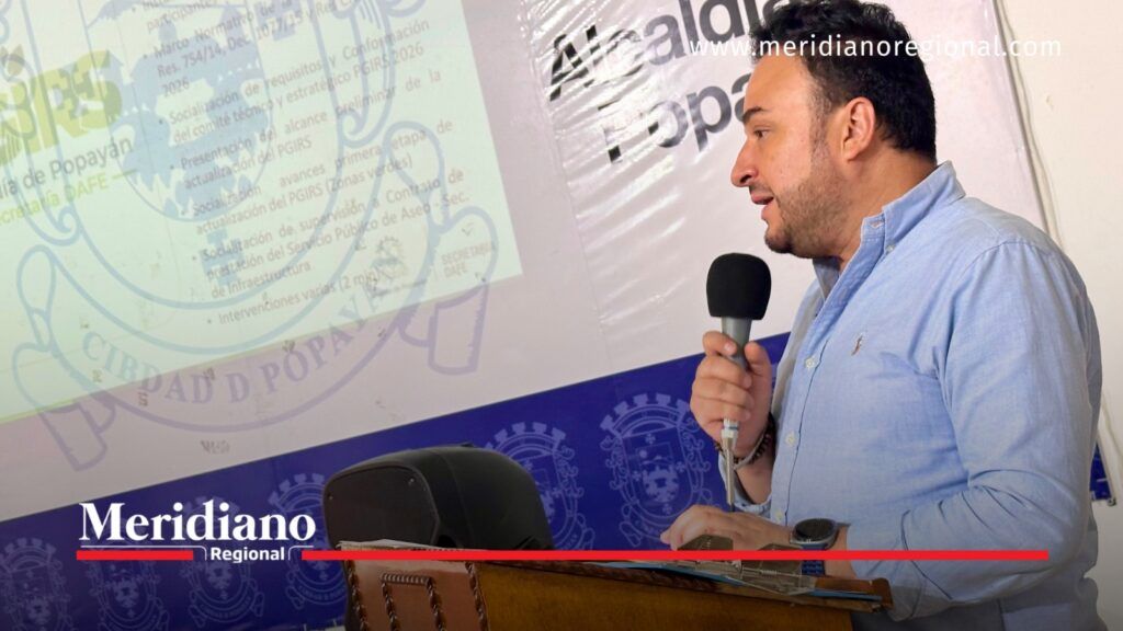 Iván Darío Arturo Pabón, secretario DAFE, habla por un micrófono frente a una presentación sobre el PGIRS de Popayán.