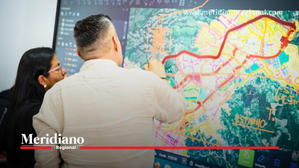 Dos personas revisan un mapa digital con trazados viales y delimitaciones territoriales en una pantalla.