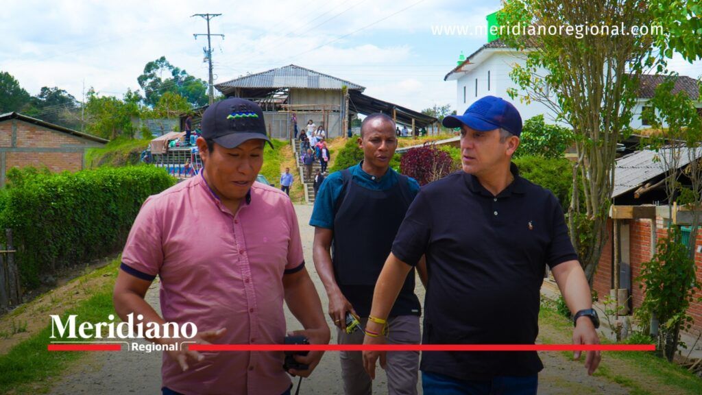 Alcalde Juan Carlos Muñoz Bravo camina acompañado por dos hombres en una vía rural sin pavimentar de Cajibío, Cauca.
