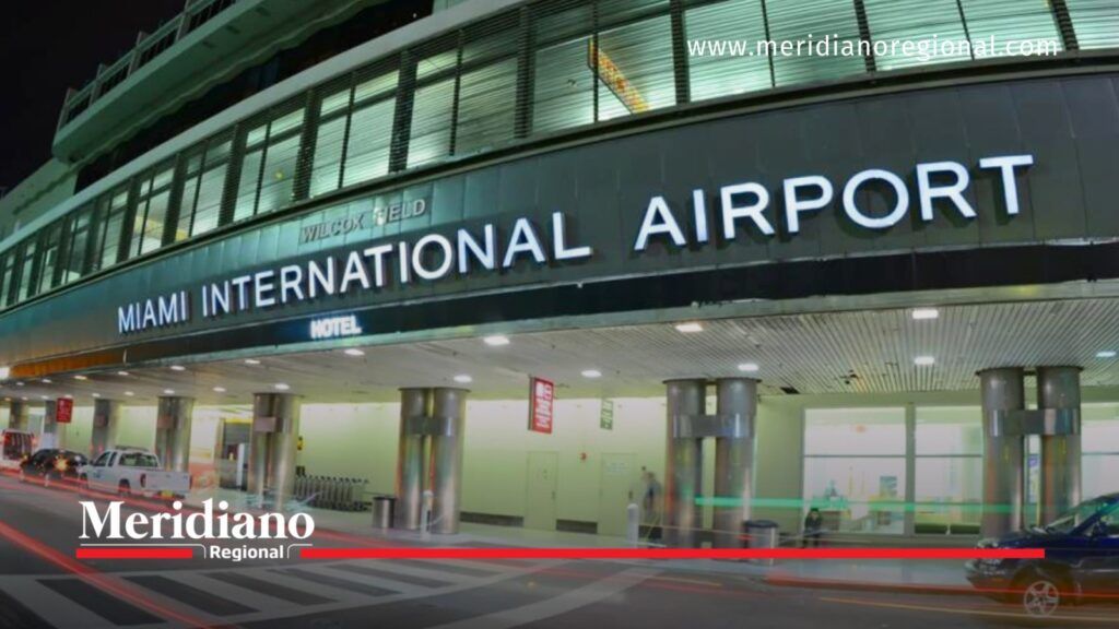 Fachada nocturna del Aeropuerto Internacional de Miami, con señalización iluminada y vehículos frente a la terminal.