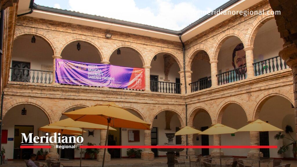 Sede de Artes y Música de la Universidad del Cauca. - Meridiano Regional Patio interior de la sede de Artes y Música de la Universidad del Cauca, con arcos de ladrillo, balcones y sombrillas.