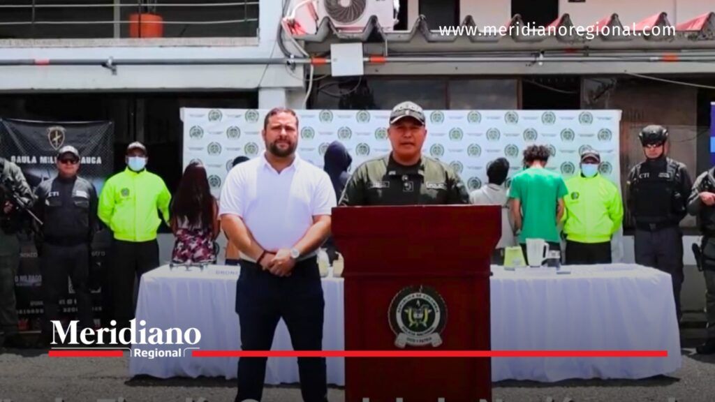 Integrante de la Policía Nacional habla desde un atril durante la presentación de un operativo contra el microtráfico en Popayán. A su alrededor se encuentran funcionarios y varias personas de espaldas.