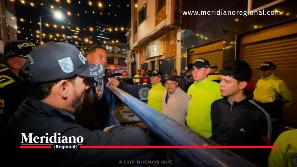 Operación Kratos en Bogotá: policías y civiles junto a una estructura de protección durante los procedimientos nocturnos.