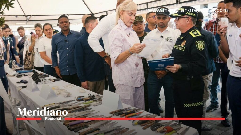 Dilian Francisca Toro y un oficial de Policía revisan documentos frente a una mesa con armas incautadas durante la megatoma en Palmira.