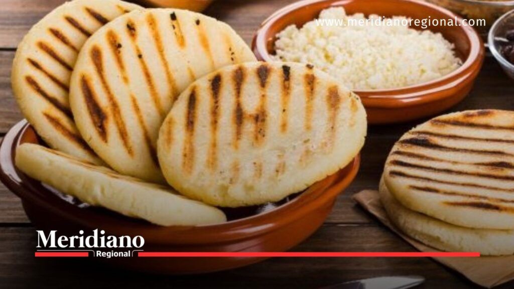 Arepas de maíz asadas y recipiente con arroz blanco sobre una mesa de madera.